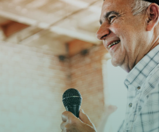 Elder speaking into a microphone at a gathering